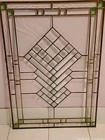 Full view of stained glass panel with diamond geometric pattern and green glass corners, brass framing