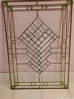 Full view of vintage stained glass panel with geometric design and green corner accents