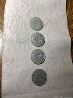 Four Canadian 5 cent coins arranged vertically on a fabric surface, showing the reverse side with denomination and maple leaf design.