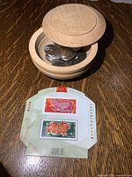 Photo of wooden trinket box with lid partially open showing coins, and the accompanying Year of the Pig stamps sheet laid out in front.