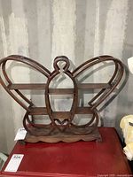 Front view of the wooden butterfly-shaped shelf showing butterfly design with multiple small shelves and scalloped base.