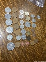 Photo showing an assortment of 38 foreign circulated coins of various sizes, metals, and designs laid out on wooden surface.