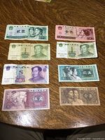 Photo showing eight different Chinese banknotes with various denominations and colors on a wooden surface.