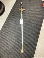 Full view of sword in scabbard laid flat on floor