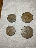 Four large old copper coins on a cloth background, showing front and back designs with ship and Britannia figure.