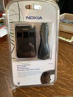 Front view of sealed Nokia HF-200 Bluetooth speakerphone packaging showing device and charger adapter inside clear blister pack with Nokia branding and product information.