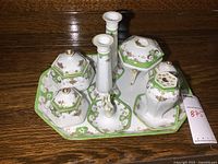 Overall group of 9-piece dresser set on wood surface showing the set with tray, trinket boxes, ring holder, flower frog, candlesticks, and hairpin holder