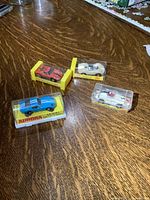 Four vintage Aurora slot cars in original boxes displayed on a wooden table.