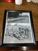 Framed black and white reprint of two wartime photos, showing soldiers marching and relaxing.