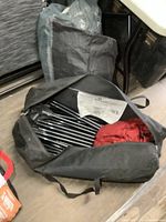 Open carry bag containing bundled tent poles and red fabric tent components on floor