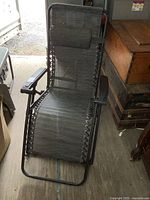 Full side view of the black zero gravity recliner chair showing metal frame, mesh seating, armrests, and folded footrest.