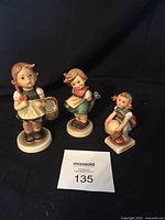 Three porcelain Goebel Hummel figurines photographed together showing frontal view