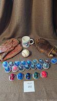 Lot contents: two vintage mitts, used baseball, Toronto Maple Leafs mug, and 21 mini helmets displayed on brown textile background.