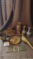 Photo showing the full lot including brass pitcher, letter holder, vases, bird plate, bird statues, and plaques on fabric backdrop