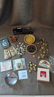 Full overview photo of all CN railway memorabilia on fabric background including buttons, pins, badges, ashtrays, paperweights, keychain and small locomotive figurine