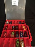 Full view of the red plastic carrying case with 12 toy cars inside, arranged in compartments under clear lid