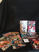 View of 9 vintage DC comic books laid out, including 5 Vigilante, 2 Men of War, 1 Sgt. Rock, 1 The Unknown Soldier.