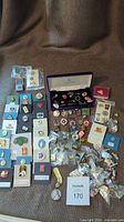 Full view of assorted vintage and souvenir pins arranged on surface, showing quantity and variety including boxed and loose pins