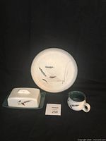 Set of three Denby Greenwheat pattern ceramic pieces: covered butter dish, small creamer, and dinner plate with green wheat design on beige background.