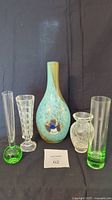 Set of five glass vases displayed against a black background showing varied shapes and colors including green, clear crackled, colorful hand-blown, and clear cube pattern styles.