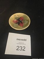 Miniature dish showing full design and size relative to a hand and a MaxSold number card