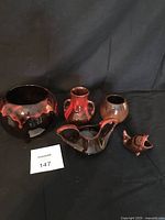 Overall group of red glazed pottery pieces on black cloth background.