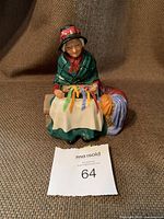 Front view of the seated figurine showing colorful ribbons and detailed clothing.