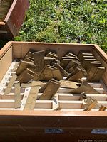 Wooden box with compartments holding multiple brass printing plates of various letters and numbers, visible engraved characters.