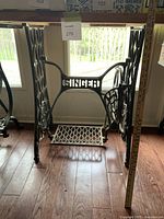 Front view of Singer treadle base showing metal frame with Singer branding and foot pedal.