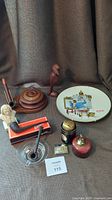 Photo showing the full lot including wooden pipe stand, pipes, lighter, statues, ashtray, and collector plate arranged on fabric background.