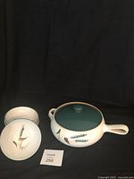 Photo showing a vintage covered casserole dish and 4 soup bowls with a small lot number card in foreground. Items display Denby Greenwheat pattern with botanical motif.