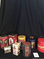 Full view of all vintage brand food tins in collection arranged on black cloth backdrop