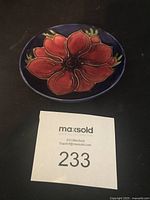 Top view of pin dish showing red anemone flower on dark blue background