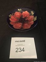 Top view of the Moorcroft Anemone pattern pin dish showing the full floral design with red petals on a dark blue background.