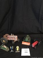 All six vintage toy farm machines arranged with a label showing lot number