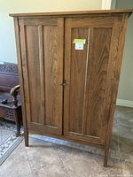 Front view of two-door stained wood wardrobe showing paneled doors and decorative hardware