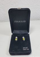 Pair of sterling silver earrings displayed in a black velvet box with labels 'STERLING SILVER' and 'GENUINE GEMSTONE'.