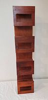 Front view of walnut wooden wall shelf showing four square compartments for wine bottle storage.