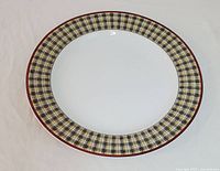 Front view showing oval ceramic serving plate with plaid check border and plain white center.