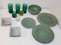 Complete lot of dinnerware and glassware displayed on white surface including the green Coventry stoneware bowl, plates, Anchor Hocking Green Tartan glasses, Starbucks cup, and square bowls.