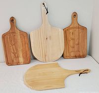 Four cutting and charcuterie boards displayed: two cactus motif wooden boards, one World Market pizza paddle, and one Italian Traditions thicker pizza paddle.