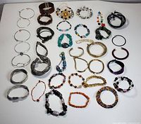 Full lot photo showing variety of 27 fashion bracelets arranged on a white background including bangles, beaded, leather, and cuff styles.