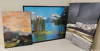 Lot includes a large photo print, signed oil on canvas painting, and two canvas prints arranged on a surface