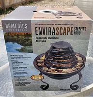 Photo of the closed original box showing the product branding and images of the fountain, highlighting the illumination feature and relaxing water sounds.