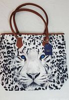 Full view of the tote bag showing the full leopard face with blue eyes and brown handles