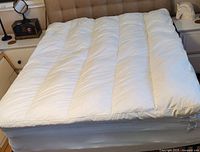 Full view of queen size white baffled featherbed on a bed, showing the complete top surface and thickness.