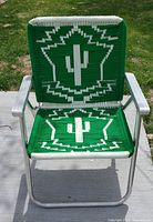 Front view of the vintage green macrame folding chair showing white cactus pattern on the seat and backrest.