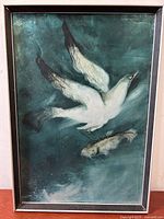 Full view of framed painting showing a white bird flying above a fish on a dark teal background.