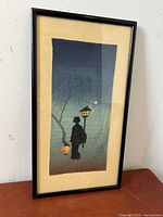 Straight-on view of entire framed print leaning against wall