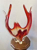 Frontal view of large crimson to amber shaded Chalet Lorraine style art glass bowl on wooden pedestal.